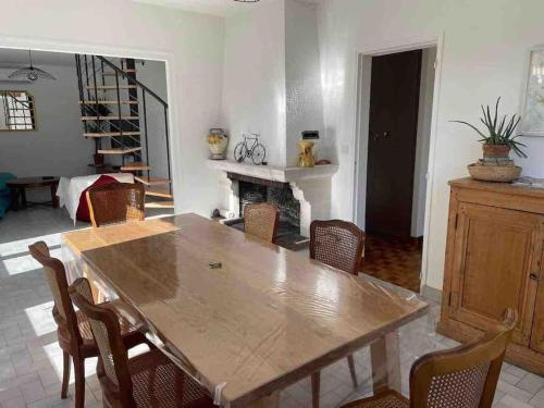 a dining room with a wooden table and chairs at Les places in Savigny-en-véron