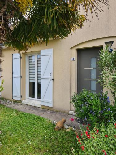 ein Haus mit zwei Türen und einem Garten mit Blumen in der Unterkunft Chambre avec salle de bain privative à 10 minutes du circuit des 24H du MANS in Étival-lès-Le Mans