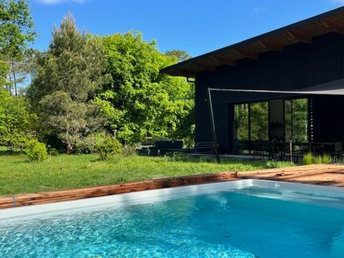 a swimming pool in front of a house at La Maison dans l'Airial, maison d'architecte en pleine nature, PISCINE in Onesse-et-Laharie