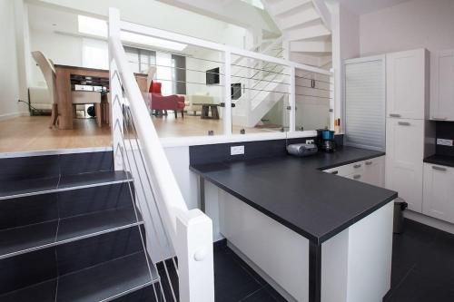 une cuisine avec un comptoir noir et un escalier dans l'établissement MAISON 4 CHAMBRES,JARDIN ET TERRASSE, proche mer,casino et place Morny, à Deauville