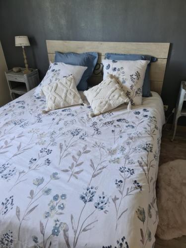 ein Bett mit einer blauen und weißen Bettdecke und Kissen in der Unterkunft Chambre avec salle de bain privative à 10 minutes du circuit des 24H du MANS in Étival-lès-Le Mans