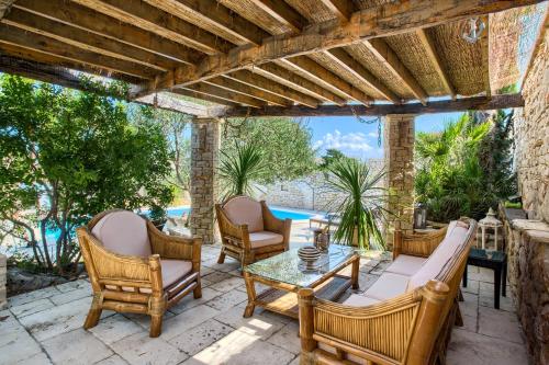 a patio with chairs and a table and a pool at Villa Kos Murter Apartments in Murter