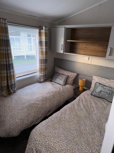a bedroom with two beds and a window at Presthaven sands P&Ts home from home in Talacre