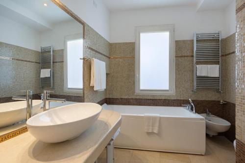 a bathroom with a large white tub and two sinks at Grand Hotel Mediterranee in Alassio