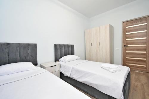 EvnAir في Pʼarakʼar: سريرين في غرفة نوم بجدران بيضاء ودواليب خشبية