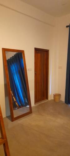 a room with a mirror and a door with blue curtains at Surf Gangs Arugambay in Arugam Bay