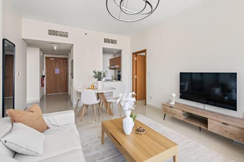 a living room with a white couch and a tv at Silkhaus Vacation Homes Chic 2 BDR Near Reem Central Park in Abu Dhabi