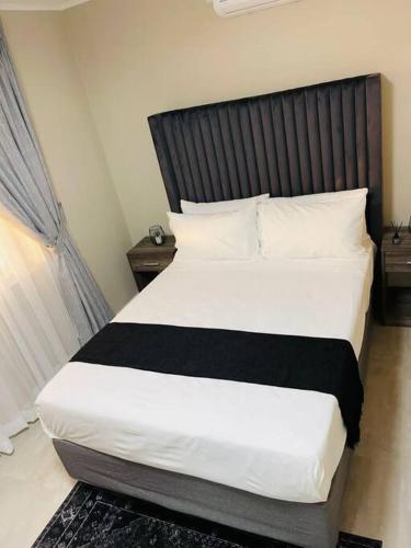 1 dormitorio con 1 cama grande y cabecero negro en Motswedi 1 bedroom apartment B9, en Gaborone