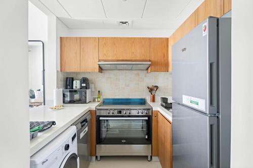 a kitchen with a stove and a refrigerator at Silkhaus Vacation Homes Convenient 1BDR Near Reem Mall in Abu Dhabi