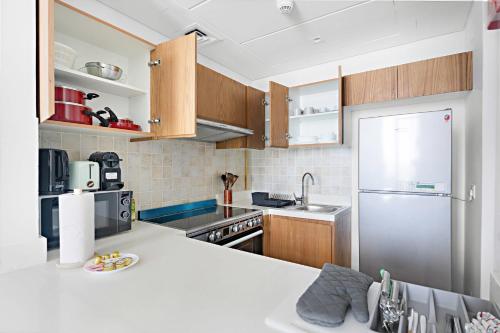 a kitchen with wooden cabinets and a stainless steel refrigerator at Silkhaus Vacation Homes Convenient 1BDR Near Reem Mall in Abu Dhabi