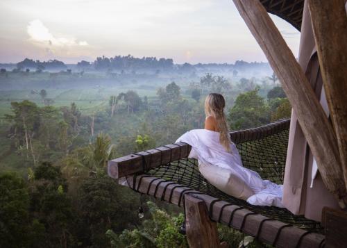 Selat的住宿－Camaya Bali - Magical Bamboo Houses，坐在建筑物阳台上的身着白色服装的女人