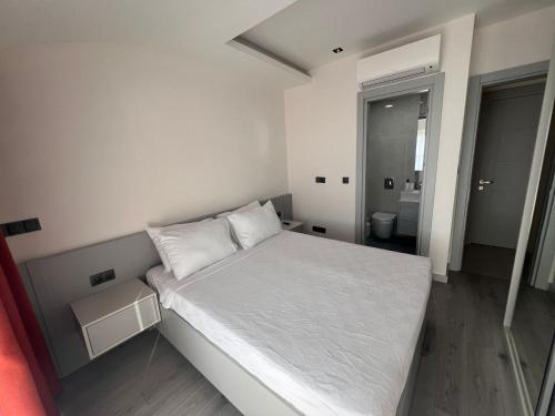 a small bedroom with a white bed and a bathroom at Ulu Panorama Residence in Alanya