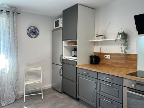 a kitchen with gray cabinets and a chair in it at Ferienwohnung Casa de Mane&Tina mit Gartenmitbenutzung in Traunreut