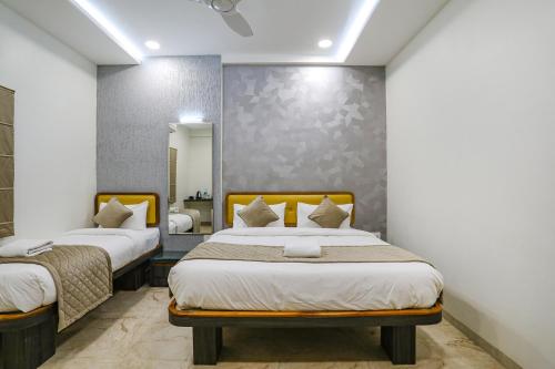 a bedroom with two beds and a mirror at FabHotel Prime Ajinkya Palace in Aurangabad