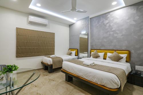 a hotel room with two beds and a mirror at FabHotel Prime Ajinkya Palace in Aurangabad