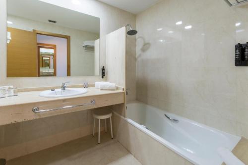 a bathroom with a sink and a tub and a mirror at VS Gandía Palace Hotel **** in Gandía