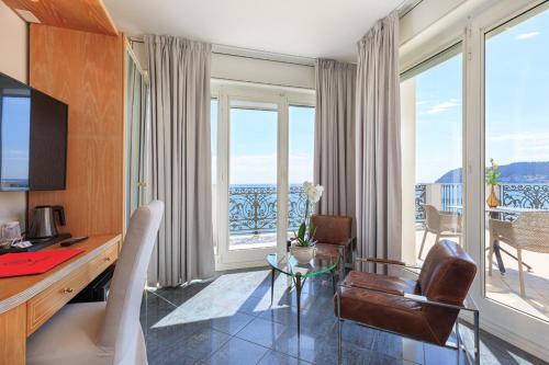 a room with a desk and chairs and a balcony at Grand Hotel Mediterranee in Alassio
