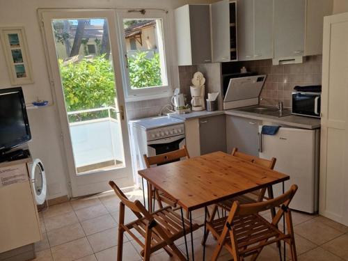 Il comprend une cuisine avec une table et des chaises en bois. dans l'établissement Appartement Hyères : 2 pièces, jardin privé, proche plage et port, WIFI, parking - FR-1-335-161, à Hyères