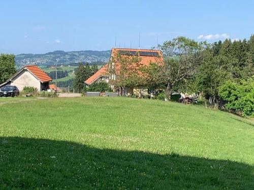 a large grassy field with a house in the background at Ferienwohnung Tiererlebnishof Windegg in Urnäsch