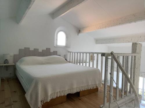 une chambre avec un lit dans une pièce blanche dans l'établissement Grand studio mezzanine avec vue mer, parking et climatisation à deux pas de la calanque de la Cron - FR-1-100-319, à Cavalaire-sur-Mer