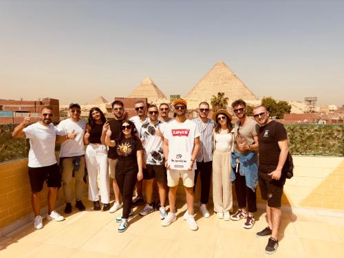 eine Gruppe von Menschen, die sich vor Pyramiden für ein Bild ausgeben in der Unterkunft Hur Pyramids Inn in Kairo