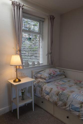 a bedroom with a bed with a lamp and a window at Water View Cottage, Conwy in Conwy