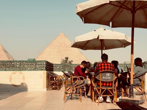 Menschen, die an einem Tisch unter einem Schirm vor den Pyramiden sitzen in der Unterkunft Hur Pyramids Inn in Kairo