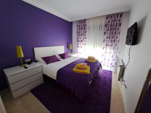 - une chambre violette avec un lit et des serviettes dans l'établissement Roda Golf gelijkvloers appartement, à Roda