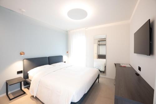 a bedroom with a white bed and a flat screen tv at Midum LuxuryApartments con giardino in Trento