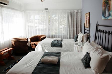 a bedroom with two beds and a living room at Janke Guest House in Kuruman