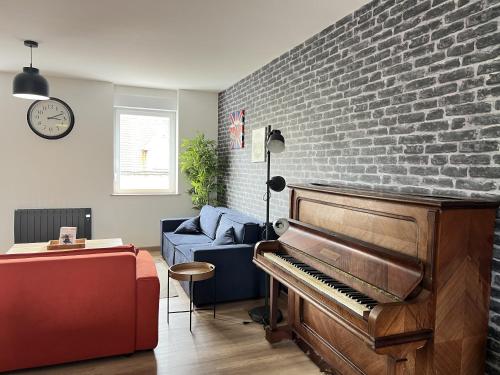 - un salon avec un piano et un mur en briques dans l'établissement Le Victor Hugo, à Calais