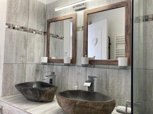 La salle de bains est pourvue d'un grand lavabo en pierre et de miroirs. dans l'établissement La Bohème, à Rochefort