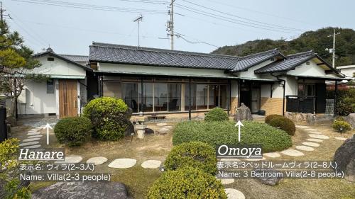 uma casa com alguns sinais em frente em Vacation House YOKOMBO em Naoshima