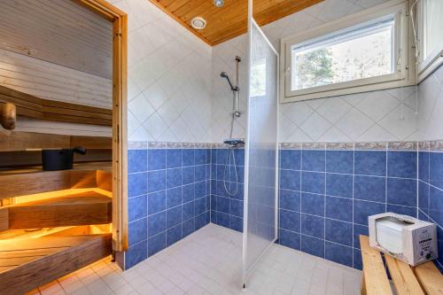 y baño con ducha de azulejos azules. en Holiday Cabin Mäntyhovi, en Kalajoki