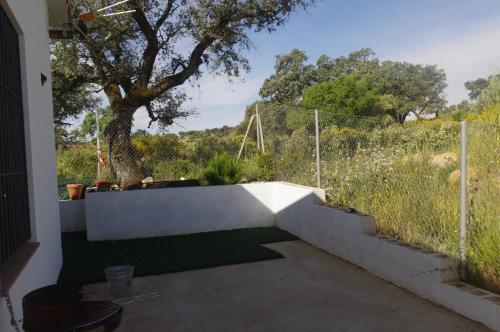 a concrete retaining wall with a tree and a fence at Villa Saudade, casa entre encinas in El Castillo de las Guardas