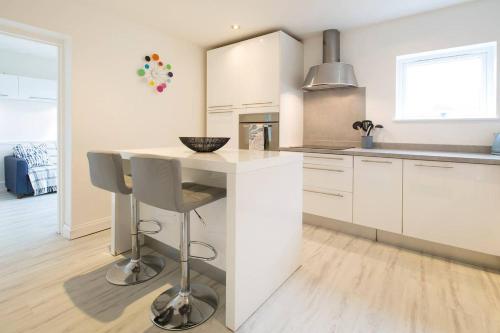 a kitchen with white cabinets and a counter with a stool at The Tardis 5 bedroom, 3 bathroom Oxford City Oasis with Free Parking in Oxford
