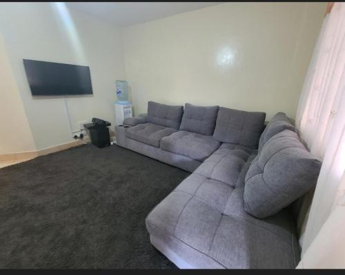 een woonkamer met een grijze bank en een flatscreen-tv bij Fancy Gateaway in Ruiru
