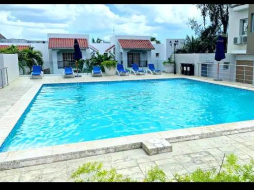 una gran piscina con sillas azules frente a una casa en Confortable apto. en Boca Chica en Boca Chica