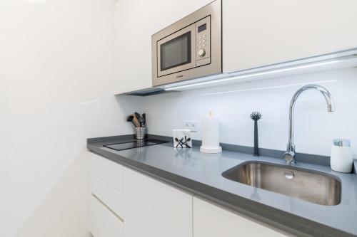 una cocina con fregadero y microondas en APARTAMENTOS FIBES GARDEN SEVILLA, en Sevilla