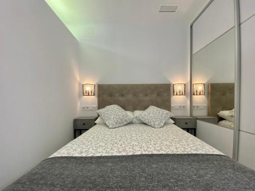 Un dormitorio con una cama con dos almohadas y un espejo. en APARTAMENTOS FIBES GARDEN SEVILLA, en Sevilla