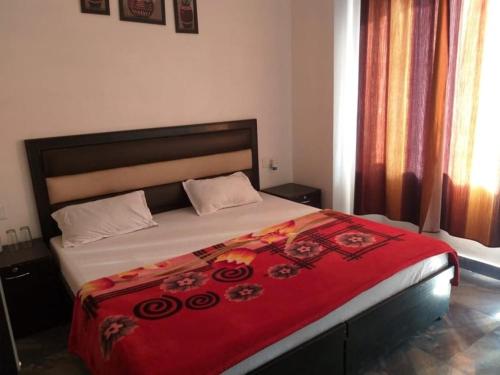 a bedroom with a large bed with a red blanket at DREAM HILLS B&B in Dalhousie