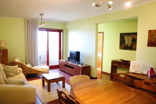 a living room with a wooden table and a tv at Sunset Apartment Vila Nova de Gaia in Vila Nova de Gaia