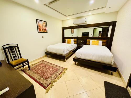 um quarto com 2 camas, uma cadeira e um espelho em Bling International Hotel Multan em Multan