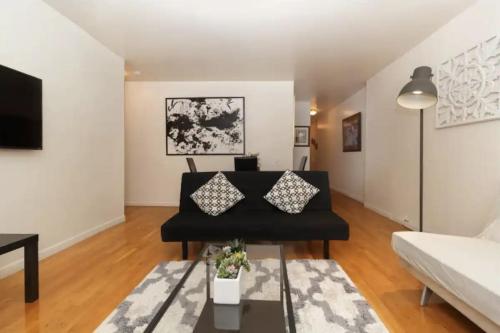 a living room with a black couch and a table at 2Bed Bliss by Central Park North in New York