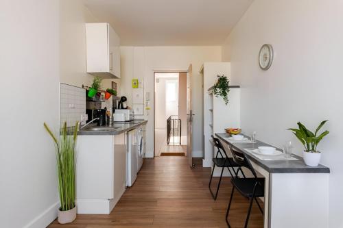 une cuisine avec des armoires blanches et un comptoir dans l'établissement Le Jungle Trefilerie Spacieux - équipé - Wifi - TV - Calme, à Saint-Étienne