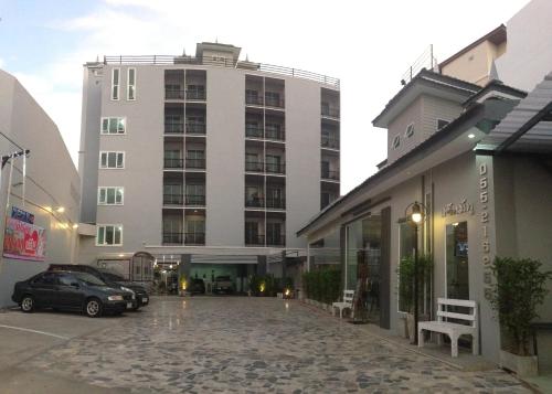 un gran edificio blanco con coches aparcados en un aparcamiento en @Me2 Hotel, en Phitsanulok