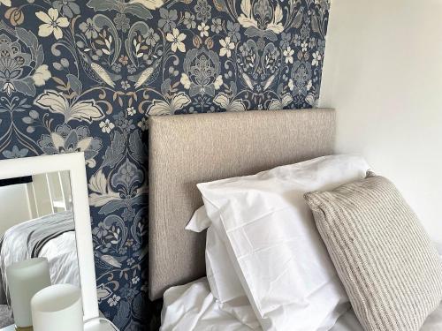 a bedroom with a bed and a wall with floral wallpaper at Meadow Lark in Old Somerby