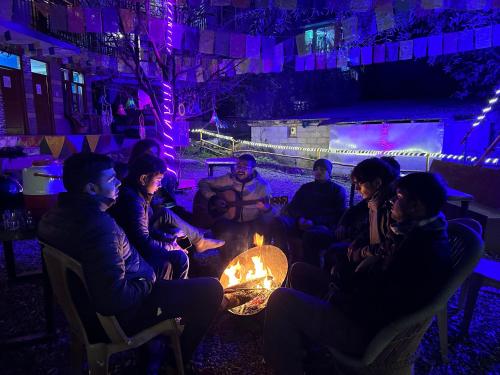 um grupo de pessoas sentadas à volta de uma fogueira à noite em Hostel 360 Degree Jibhi em Jibhi