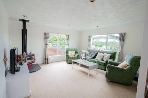 a living room with two green couches and a tv at Big sale in winter three bedrooms two bathrooms in karori in Wellington