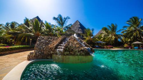 a pool at a resort with a fountain at Tembo Court Apartments in Malindi